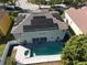 Aerial view of a home with solar panels, a pool and spa, and a paved backyard at 7801 Belvoir Dr, Orlando, FL 32835