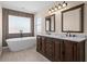 Bathroom featuring a soaking tub, wood accent wall, dual sinks, and marble countertops at 7801 Belvoir Dr, Orlando, FL 32835