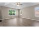 Bedroom featuring wood-look floors, tray ceiling, and ample natural light at 7801 Belvoir Dr, Orlando, FL 32835