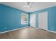 Blue bedroom with a ceiling fan, wood-look floors, and natural light at 7801 Belvoir Dr, Orlando, FL 32835