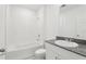 A pristine bathroom featuring a tiled shower-tub combo, granite countertop, and a large, bright mirror at 1542 Mermaid Way, Haines City, FL 33844