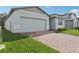 The home has a brick driveway, a two-car garage, and a manicured front yard at 1542 Mermaid Way, Haines City, FL 33844