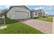 A one-story home featuring a brick driveway, two-car garage, and manicured front yard at 1542 Mermaid Way, Haines City, FL 33844