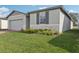 The manicured lawn highlights the light gray exterior with stone accents and brick driveway at 1542 Mermaid Way, Haines City, FL 33844