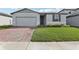 Charming one-story home with a well-manicured lawn, brick driveway, and gray trim at 1542 Mermaid Way, Haines City, FL 33844