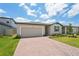 View of a single-story home featuring a brick driveway, garage, and lush lawn under a cloudy sky at 3824 Giorgio Dr, Winter Haven, FL 33884