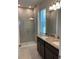 Bright bathroom showcasing a walk-in shower with glass door, double vanity with granite counter, and modern lighting at 1926 Church Lake St, Groveland, FL 34736