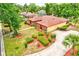 Aerial view showcasing a well-landscaped home with a brick and yellow exterior, a long driveway, and mature trees at 1546 Stormway Ct, Apopka, FL 32712