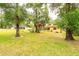 Secluded backyard with mature trees, a cozy patio, and a glimpse of the home's charming screened-in porch at 1546 Stormway Ct, Apopka, FL 32712