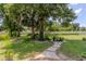 Large backyard featuring mature trees, a lush lawn, and a brick-lined walkway at 1546 Stormway Ct, Apopka, FL 32712