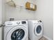Bright laundry room with a white Samsung washer and dryer and storage shelf at 5200 Landmark Dr, St Cloud, FL 34771