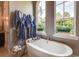Brightly lit bathtub area with garden views, potted plants, and blue luxury bathrobes at 16828 Vinci Way, Montverde, FL 34756