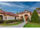 Stunning exterior view of a home with a tile roof, arched entry, and lush, well-maintained landscaping at 16828 Vinci Way, Montverde, FL 34756