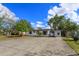 An exterior view showcasing a white house with modern design, complemented by a spacious driveway and green landscaping at 220 Lake Gene Dr, Longwood, FL 32779