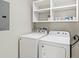 An ample laundry room with a washer, dryer, and overhead shelving at 7573 Laureate Blvd # 1301, Orlando, FL 32827