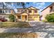 Two-story house with a yellow facade, brick driveway, and landscaping at 10064 Silver Laurel Way, Orlando, FL 32832