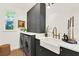 Modern laundry room featuring dark cabinets, farmhouse sink, and sleek washer and dryer at 16161 Parkwyn St, Winter Garden, FL 34787