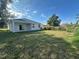 Expansive backyard featuring a covered patio and ample space for outdoor activities under a bright, partly cloudy sky at 4445 America St, Orlando, FL 32811