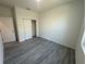 Bedroom with gray wood-look floors, white paint, closet, and natural light at 4445 America St, Orlando, FL 32811