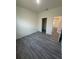 Bright bedroom with gray wood-look floors and white paint, leading to other rooms at 4445 America St, Orlando, FL 32811