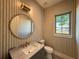 Stylish powder room with patterned wallpaper, round mirror, and a gray vanity with marble countertop at 1730 Winchester Dr, Winter Park, FL 32789