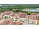 Aerial view of a townhome community with tile roofs, lush landscaping and a lake in the distance at 2444 Lobelia Dr, Lake Mary, FL 32746