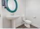 Small bathroom with pedestal sink, turquoise mirror, and wood-look floors at 2444 Lobelia Dr, Lake Mary, FL 32746