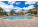 A large in-ground community pool surrounded by lounge chairs, palm trees and blue skies at 12855 Madison Pointe Cir # 106, Orlando, FL 32821