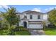 Elegant two-story home with white exterior, well-maintained landscaping, and a patterned driveway leading to an attached garage at 1548 Moon Valley Dr, Davenport, FL 33896