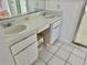 Bright bathroom with double sinks, white cabinetry, and tile flooring at 5610 King James Ave, Leesburg, FL 34748