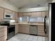 Neutral kitchen featuring stainless steel appliances, light wood cabinetry, and sleek tile flooring at 5610 King James Ave, Leesburg, FL 34748