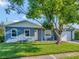 Ranch-style home with blue exterior, green lawn, and mature tree at 7685 Ceres Dr, Orlando, FL 32822