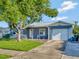 Blue house with a white garage door and a large tree in the front yard at 7685 Ceres Dr, Orlando, FL 32822