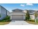 Two-story home featuring a neutral color palette, gray roof, two car garage, and manicured landscaping at 1211 Teal Creek Dr, St Cloud, FL 34771