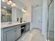 Bright bathroom featuring double vanity, white countertops, tiled floors, and glass-enclosed shower at 16744 Sanctuary Dr, Winter Garden, FL 34787
