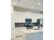Modern kitchen featuring white cabinets, quartz countertops, and stainless steel appliances at 366 Switchgrass Loop, Minneola, FL 34715