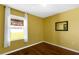 Bright bedroom featuring hardwood floors, a window with white curtains, and yellow painted walls at 205 Hamlet Rd, Davenport, FL 33837