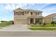 Inviting two-story home featuring red shutters, a two-car garage, screened in porch, and well-maintained landscaping at 205 Hamlet Rd, Davenport, FL 33837