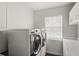 Clean laundry room equipped with modern washer and dryer and built-in storage at 12428 Summerport Ln, Windermere, FL 34786