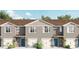 Charming townhomes boast a modern facade with blue doors, white garages, and neatly manicured landscaping at 559 Zinfandel Dr, Holly Hill, FL 32117