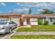 Single-story home with attached garage, manicured lawn, and lush landscaping for inviting curb appeal at 5875 Talavera St, Orlando, FL 32807