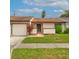Charming single-story home featuring an attached garage, a well-maintained lawn, and beautiful, mature landscaping at 5875 Talavera St, Orlando, FL 32807