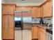 Spacious kitchen featuring stainless steel refrigerator and matching wooden cabinets with granite countertops at 5875 Talavera St, Orlando, FL 32807