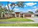 Charming brick home with well-manicured lawn, mature trees and a two-car garage on a sunny day at 250 Shady Oaks Cir, Lake Mary, FL 32746