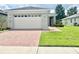 House exterior featuring a white garage door and red brick paver driveway at 3201 Songbird Cir, Harmony, FL 34773