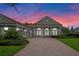 Gray house with columns, brick driveway, and sunset in the background at 6533 Cartmel Ln, Windermere, FL 34786