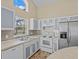 Charming kitchen featuring white cabinetry, modern appliances, and a large window at 2977 Kokomo Loop, Haines City, FL 33844
