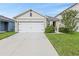 Tan house with white garage door and landscaping at 2321 Tay Wes Dr, Saint Cloud, FL 34771