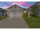 Tan house with white garage door and landscaping; sunset in background at 2321 Tay Wes Dr, Saint Cloud, FL 34771