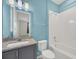 Bright bathroom features a vanity with gray cabinets and shower over tub with white tile at 687 Irvine Ranch Rd, Kissimmee, FL 34759